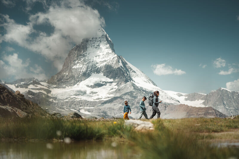 Hikers walking beside an alpine lake with the Matterhorn in the background